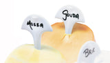 Swissmar Cheese Flags with cheese names written on them, sticking out of cheese